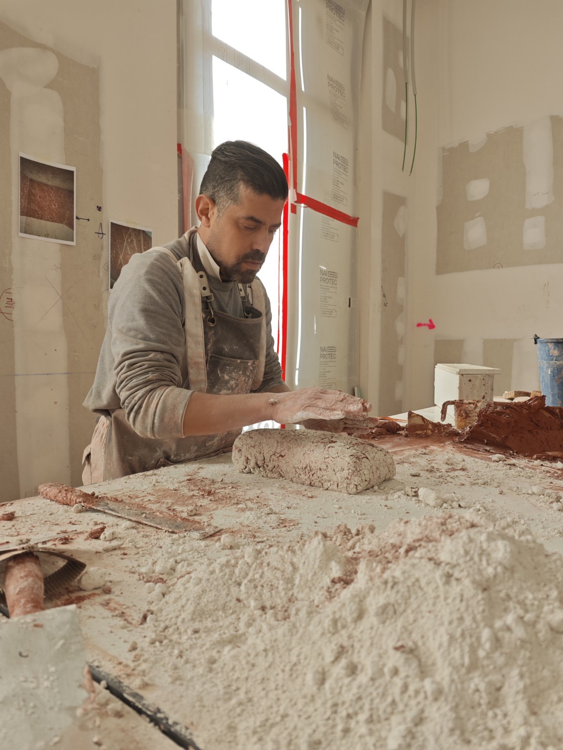 Juan Carlos Cortes García preparando una mezcla a mano sobre la mesa de trabajo
