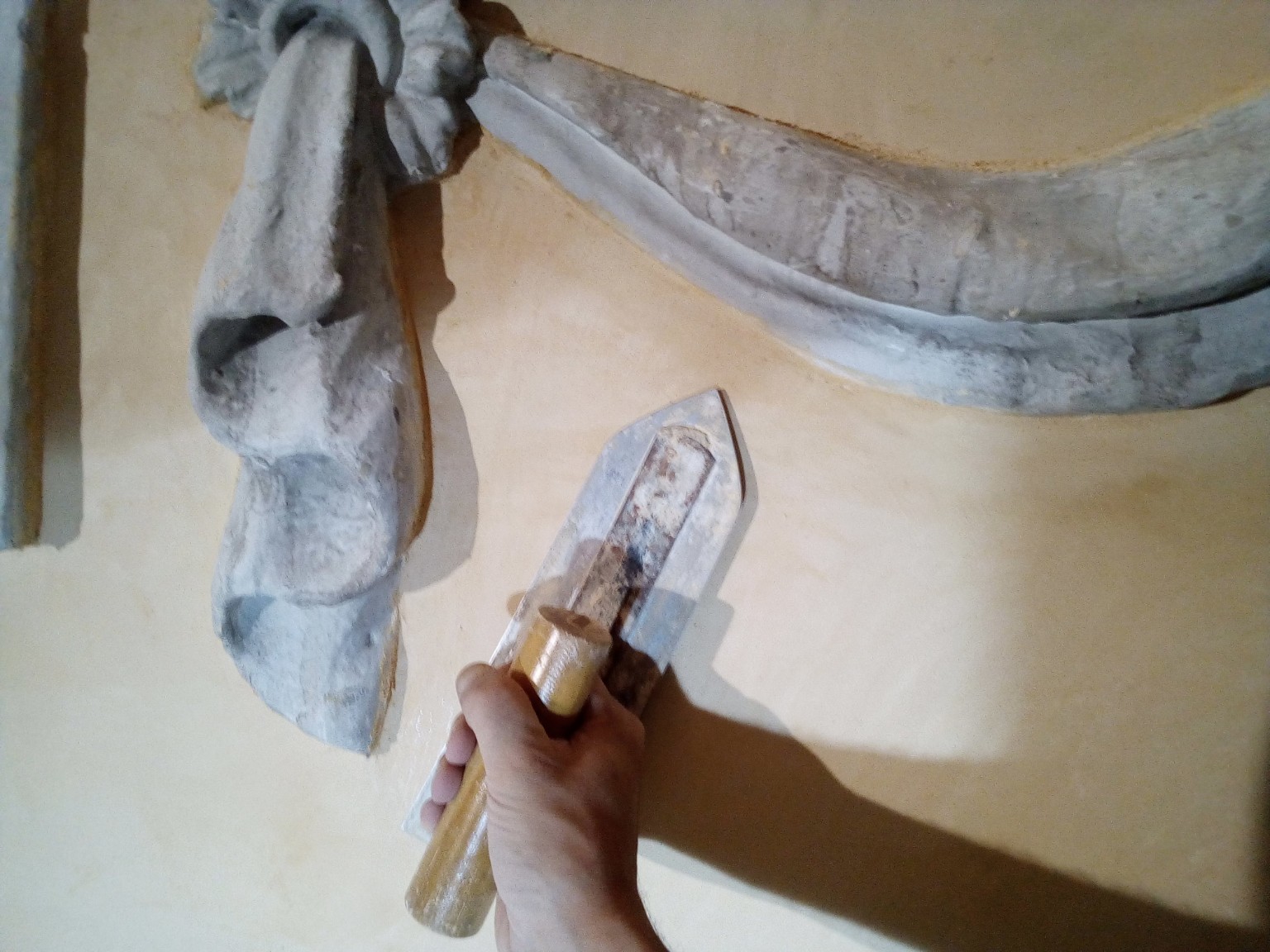Llana trabajando una superficie ocre junto a un relieve con forma de paño